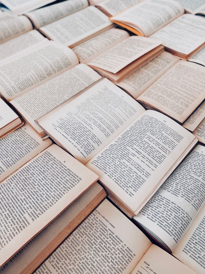 High-angle view of multiple open books arranged on a flat surface, showing written pages.
