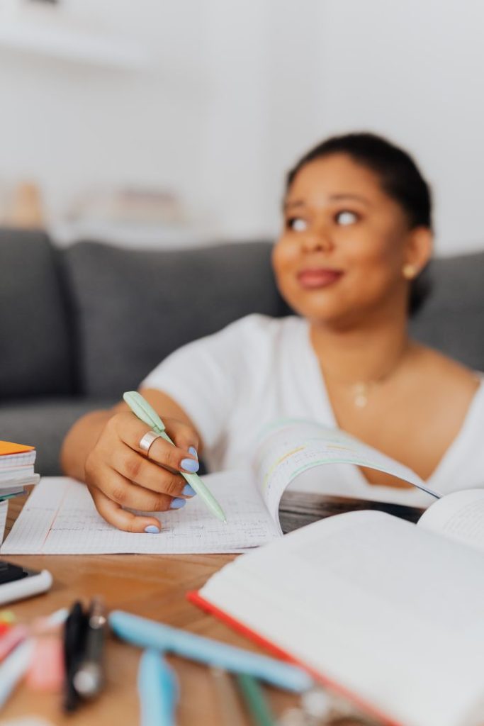 Young black woman writing in a notebook while studying indoors.