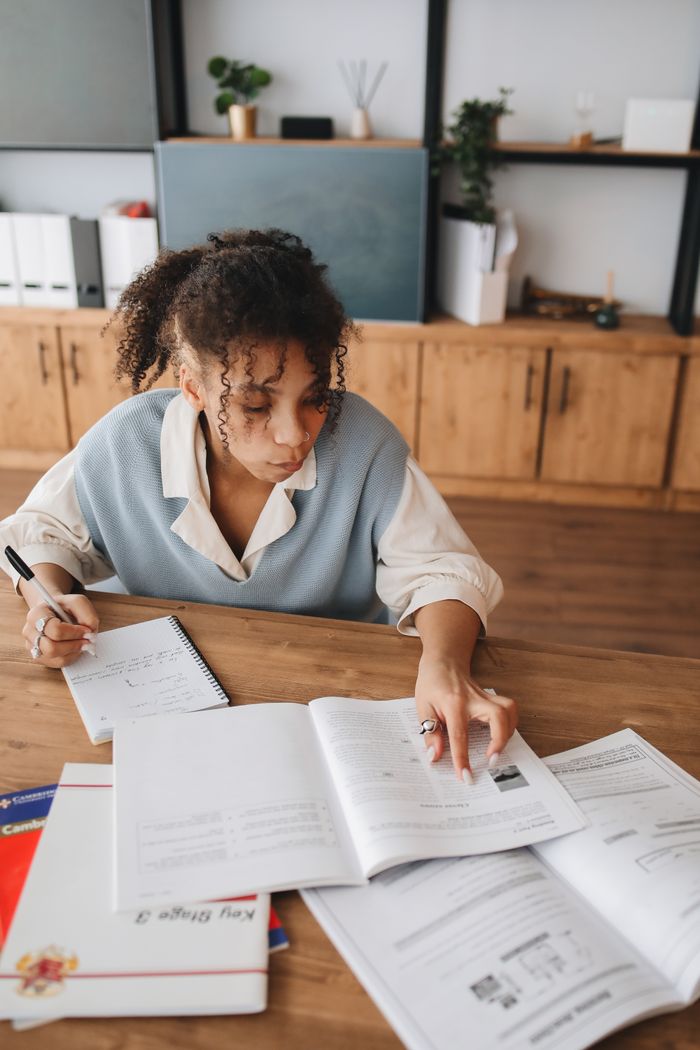 Focused young woman taking notes and studying in a cozy home office setting.